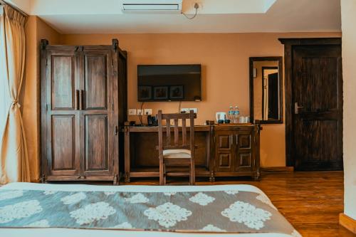 a bedroom with a bed and a desk with a television at Hotel Thamel House - 6 km from Boudhanath Stupa, Kathmandu in Kathmandu