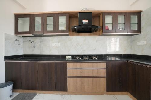 a kitchen with wooden cabinets and a black counter top at Premium Two Bedroom Apartment in Bengaluru