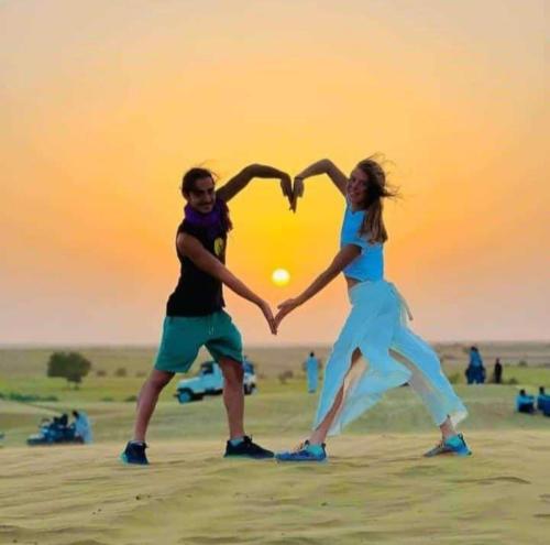 a man and a woman making a heart sign with their hands at Aroma Desert Safari Camp in Sām