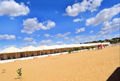 a row of white tents on a sandy beach at Aroma Desert Safari Camp in Sām