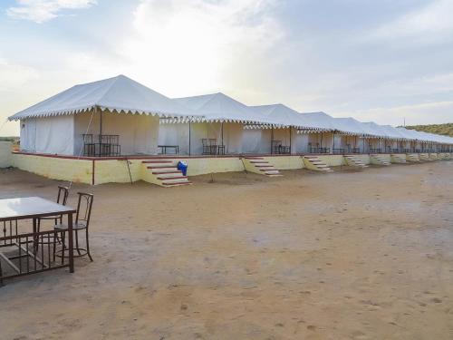 a row of tents in the desert with tables and chairs at Aroma Desert Safari Camp in Sām