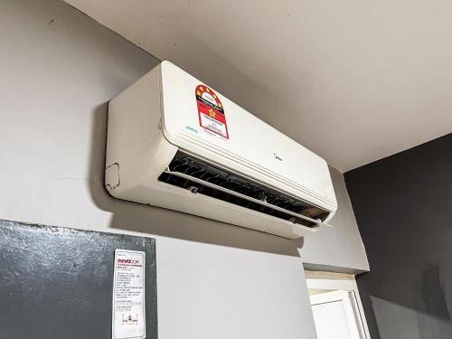 a white air conditioner on top of a refrigerator at Ho Hotel Batu Berendam C in Malacca