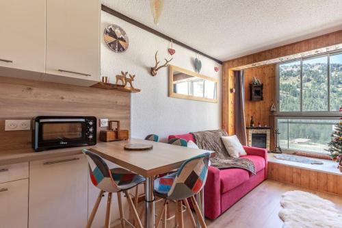 - une cuisine et un salon avec un canapé rose et une table dans l'établissement Chaleureux studio, wifi, local à ski, pieds pistes, à Isola 2000