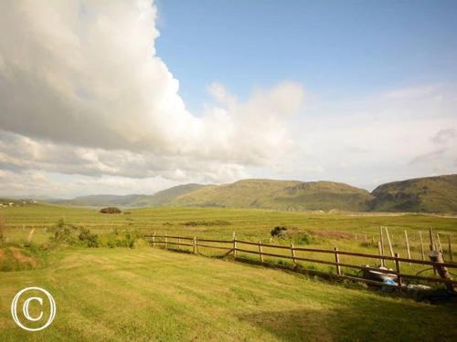 a fence in a field with mountains in the background at Atlantic Coast in Ardara