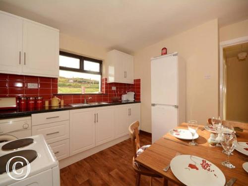 a kitchen with a table and a white refrigerator at Atlantic Coast in Ardara