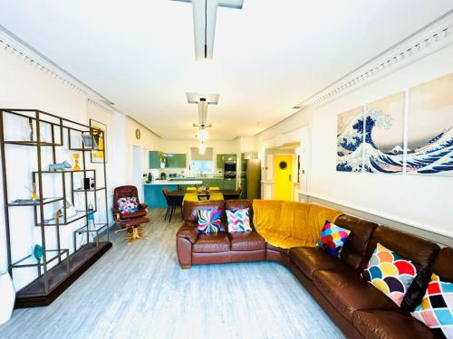 a living room with a brown leather couch and a kitchen at New Waverleys Retreat Stunning Loft Style Ventnor in Ventnor