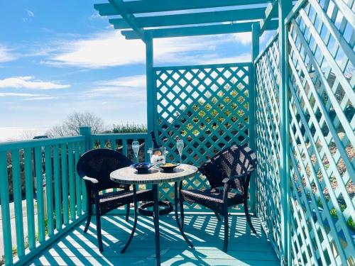 two chairs and a table on a deck with a blue fence at New Waverleys Retreat Stunning Loft Style Ventnor in Ventnor