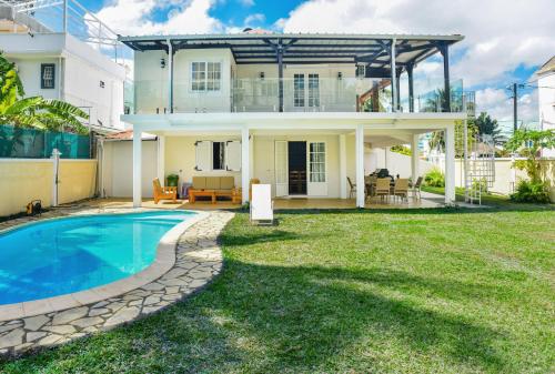 a villa with a swimming pool in front of a house at La Villa Côtière 2 in Flic-en-Flac