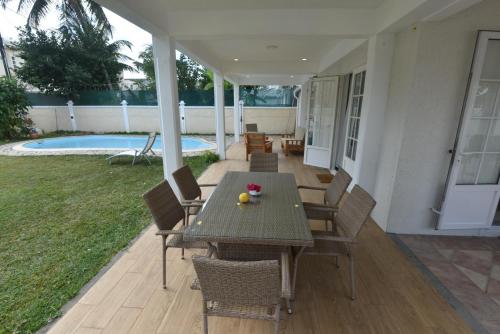 a patio with a table and chairs and a pool at La Villa Côtière 2 in Flic-en-Flac
