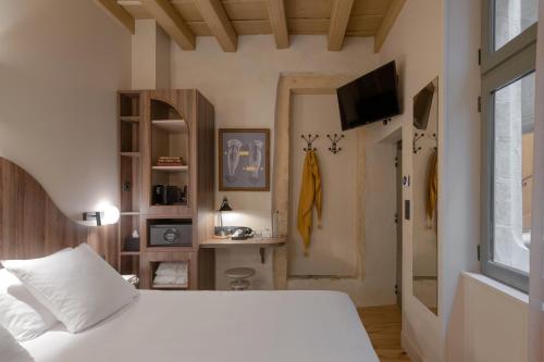 a bedroom with a white bed and a television at Académie Hôtel Lyon in Lyon