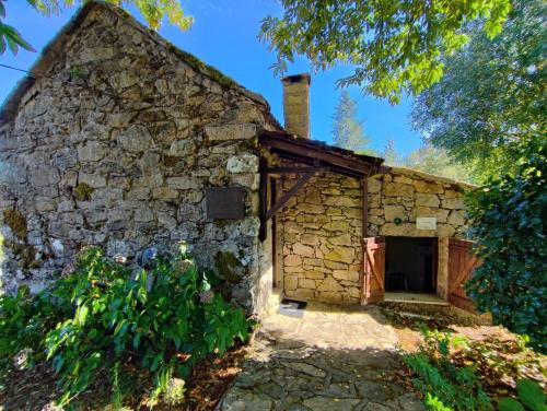 Un antiguo edificio de piedra con una puerta y un árbol. en Casa da Fonte - Branda da Aveleira, en Melgaço