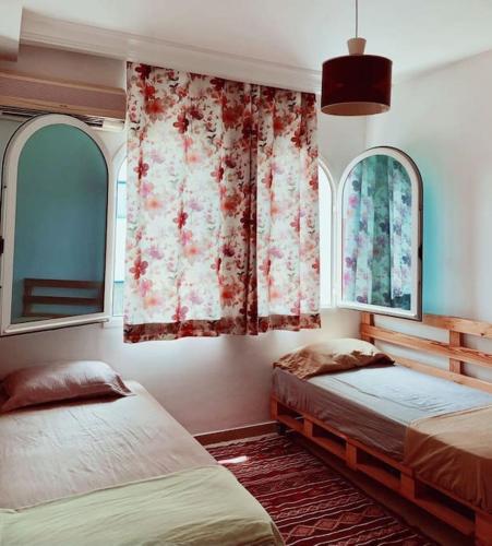 ein Schlafzimmer mit zwei Betten und zwei Fenstern in der Unterkunft Appartement Hammamet Nord in Hammamet Nord