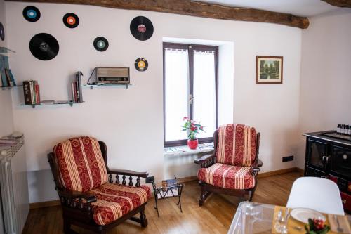 a living room with two chairs and records on the wall at Agriturismo Ca' del Clat in Bagnolo Piemonte