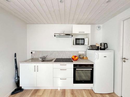 une cuisine blanche avec un évier et une cuisinière dans l'établissement L'Hirondelle, studio rénové au coeur d'Arago, à Les Sables-dʼOlonne