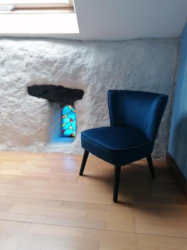 a blue chair sitting in a room with a wall at Chambres d'hôtes Kersonan in Saint-Jean-Brévelay