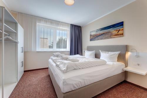 a large white bed in a bedroom with a window at Ferienhaus 6 Schlafzimmer mit Sauna UnserUsedom Ostseebad Koserow Insel Usedom in Ostseebad Koserow
