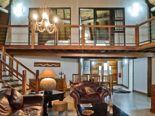 a living room with a staircase and a chandelier at Silverstreams Lodge, Villas & Cottages, Oribi Gorge in Glendale