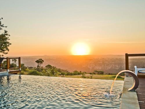 a infinity pool with the sunset in the background at Silverstreams Lodge, Villas & Cottages, Oribi Gorge in Glendale