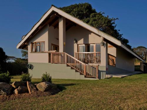 a white house with a porch and a balcony at Silverstreams Lodge, Villas & Cottages, Oribi Gorge in Glendale