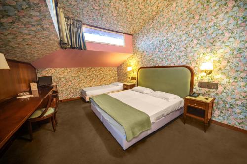 a bedroom with a bed and a desk and a window at Grand Hotel Bastiani in Grosseto