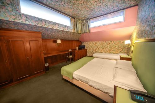 a small bedroom with a bed and two windows at Grand Hotel Bastiani in Grosseto