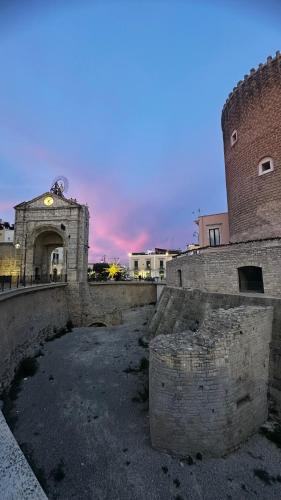 an old brick building with a tower with a clock at B&B Porta Baresana in Bitonto