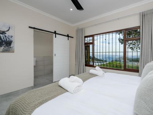 a white bedroom with a large bed and a large window at Silverstreams Lodge, Villas & Cottages, Oribi Gorge in Glendale