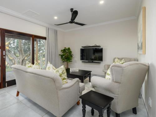 a living room with two chairs and a tv at Silverstreams Lodge, Villas & Cottages, Oribi Gorge in Glendale