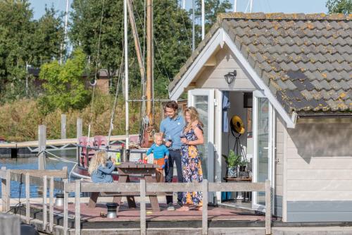 a family standing on a dock next to a small house at Marinaparcs Almere in Almere