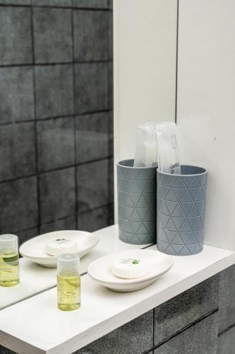 a bathroom counter with two plates and two glasses at Cozy apartment in city center in Belgrade