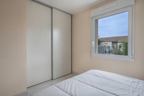 ein weißes Schlafzimmer mit einem Fenster und einem Bett in der Unterkunft Maison de plain-pied - quartier calme pour six personnes in La Plaine-sur-Mer