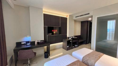 a bedroom with a bed and a desk in a room at Grandia Hotel in Bandung