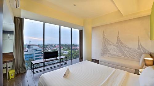 a hotel room with a bed and a tv at Whiz Prime Hotel Khatib Sulaiman Padang in Padang