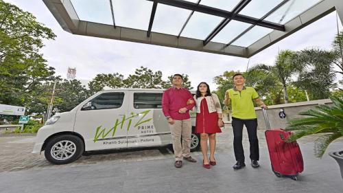 a group of three people standing in front of a van at Whiz Prime Hotel Khatib Sulaiman Padang in Padang