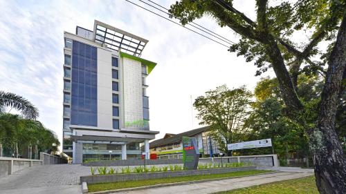 a tall building with a tree in front of it at Whiz Prime Hotel Khatib Sulaiman Padang in Padang
