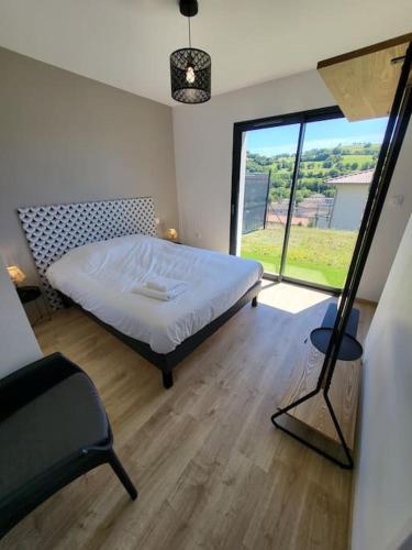 a bedroom with a bed and a large window at Rez-de-jardin de Maison avec spa et borne d'arcade in Aurillac