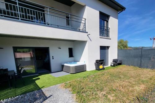 a white house with a hot tub in the yard at Rez-de-jardin de Maison avec spa et borne d'arcade in Aurillac