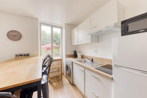 une cuisine avec des armoires blanches et un comptoir en bois dans l'établissement Cocon Cozy - 10 min Disney - Cozy Houses, à Bussy-Saint-Georges