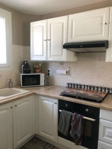 une cuisine avec des armoires blanches et un four à plaques de cuisson dans l'établissement Ambiance provençale, à La Seyne-sur-Mer