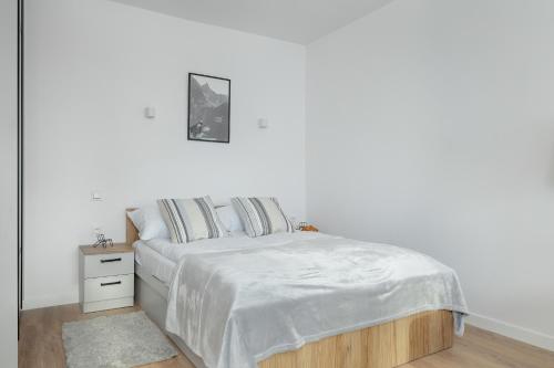 a white bedroom with a bed and a night stand at Mountain Corner Apartment in Zakopane by Noclegi Renters in Zakopane
