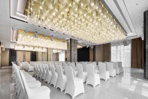 a conference room with white chairs and a large chandelier at Grand Mercure Wuhan Hanyang in Wuhan
