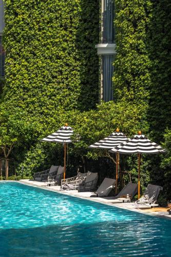a swimming pool with umbrellas and lounge chairs and a swimming pool at The Salil Hotel Riverside Bangkok in Bangkok