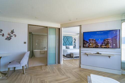 a room with a bed and a television on a wall at The Salil Hotel Riverside Bangkok in Bangkok