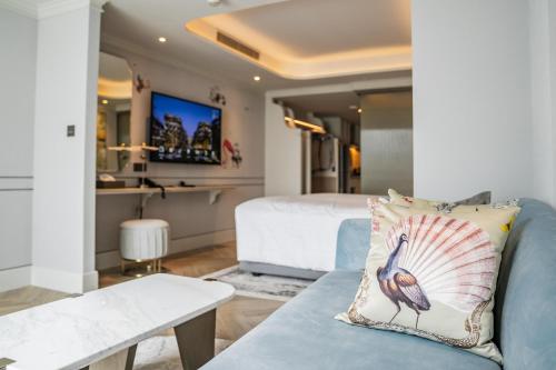 a living room with a blue couch and a bed at The Salil Hotel Riverside Bangkok in Bangkok