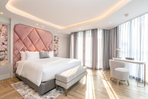 a bedroom with a large bed with a pink headboard at The Salil Hotel Riverside Bangkok in Bangkok