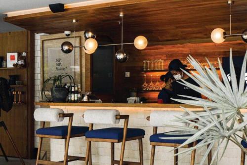 a kitchen with a bar with chairs and a woman at The Salil Hotel Riverside Bangkok in Bangkok