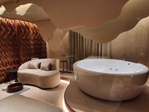 a bathroom with a bath tub and a chair at The Salil Hotel Riverside Bangkok in Bangkok