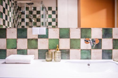 a bathroom with a sink and a green and white tiled wall at Apartament Mikołowska z balkonem in Gliwice