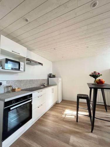 une cuisine avec une table et une cuisinière four supérieur dans l'établissement La Mouette, studio niché au coeur d'Arago, à La Rudelière