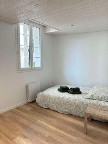 une chambre blanche avec un lit et une fenêtre dans l'établissement La Mouette, studio niché au coeur d'Arago, à La Rudelière